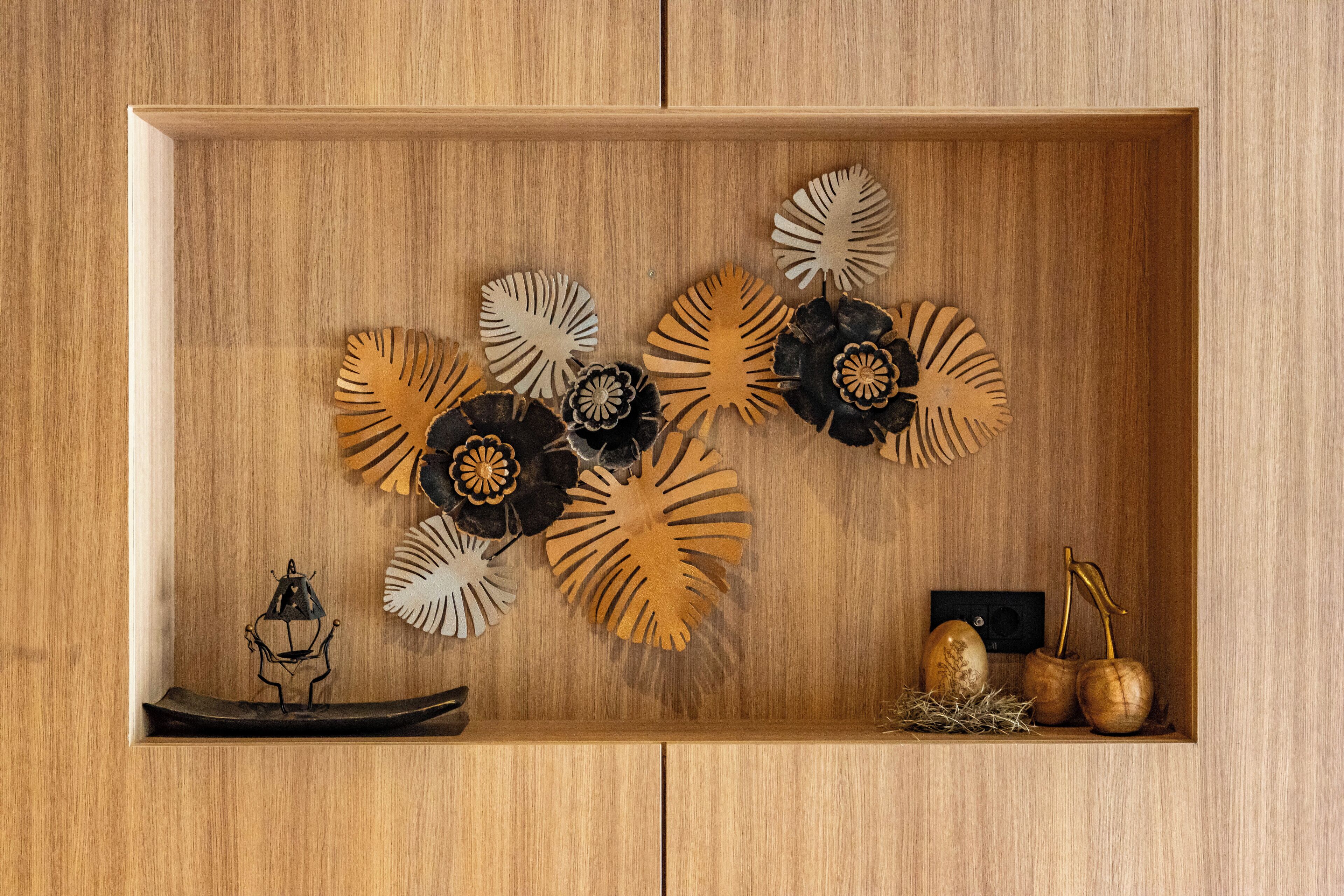 A wooden cabinet with decorative wooden leaves and a small figurine.