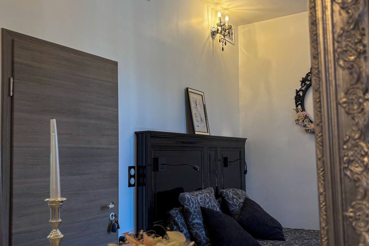 A bedroom with a bed, a dresser, a mirror, and a vase with flowers.