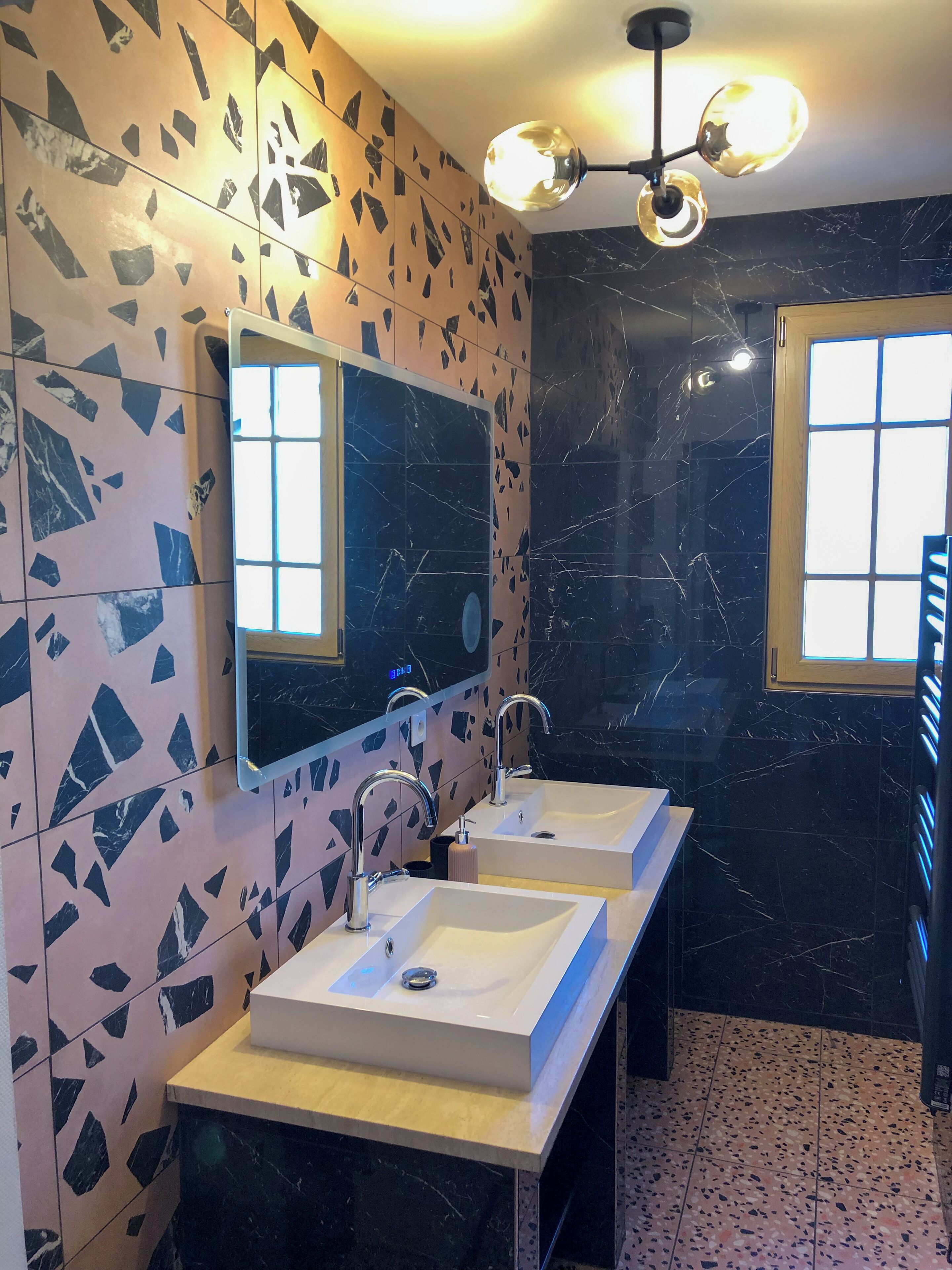 Een moderne badkamer met twee wasbakken, een grote spiegel en een plafondlamp.
