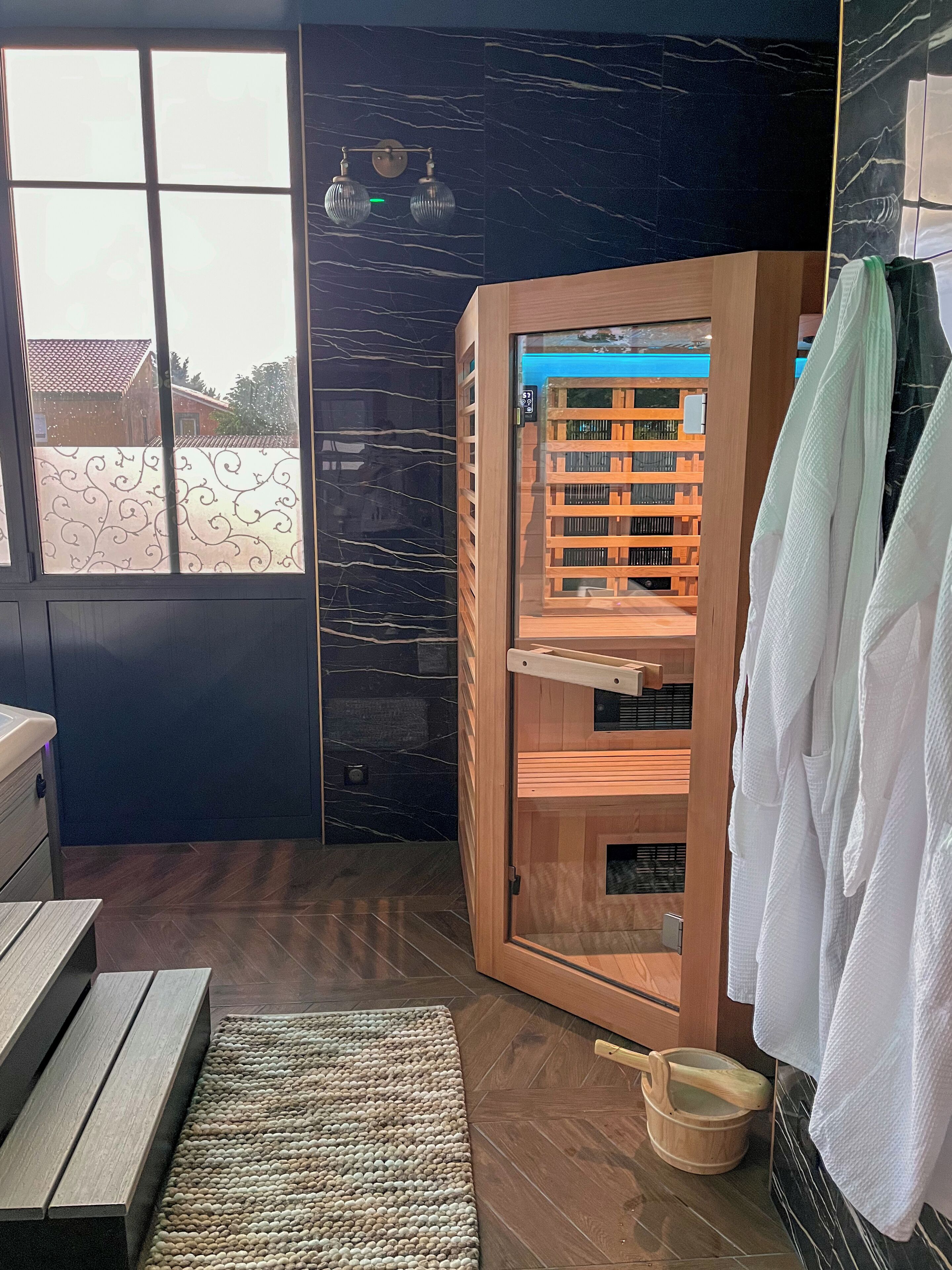 A modern bathroom with a wooden cabinet, a window with a view, and a wooden bench.