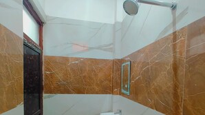 Ένα μπάνιο με νιπτήρα, καθρέφτη, ντους και μαρμάρινοι τοίχοι.