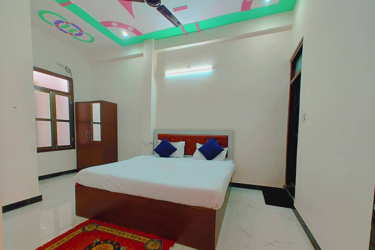 Un dormitorio con cama, armario, ventana y lámpara en el techo.