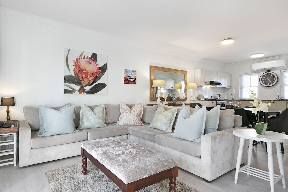 A modern living room with a sectional sofa, a coffee table, and a dining area with a small table and chairs.