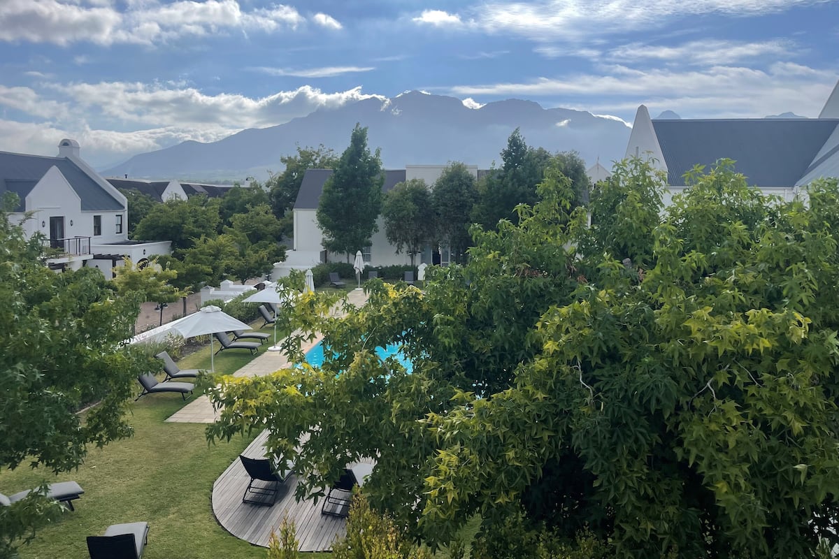 A resort with a pool, lounge chairs, and a view of mountains.