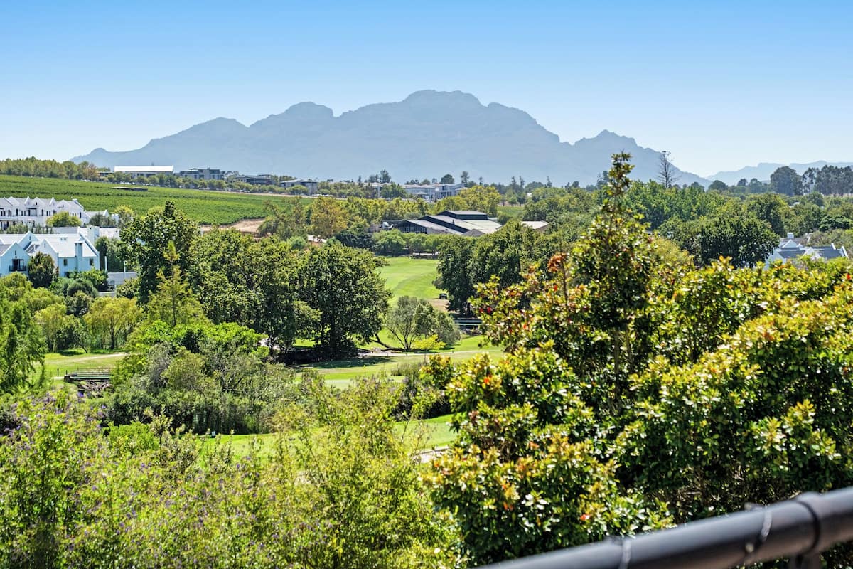 A scenic view of a golf course with buildings and mountains in the background.