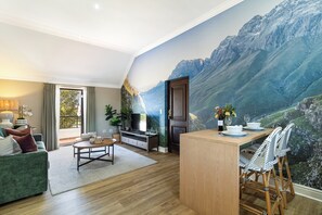 Un salon moderne comprenant un coin repas, une grande fresque représentant une montagne et une vue sur l’extérieur.
