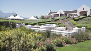 Ein großes, modernes Gebäude mit angelegtem Garten und weißen Zelten.