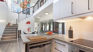 A modern kitchen with a central island, built-in appliances, and a staircase leading to an upper level. - Winelands Golf Lodges 1 (Cape Town)