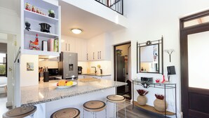 A modern kitchen with white cabinets, a granite countertop, and a built-in island with bar stools. - Winelands Golf Lodges 1 (Cape Town)