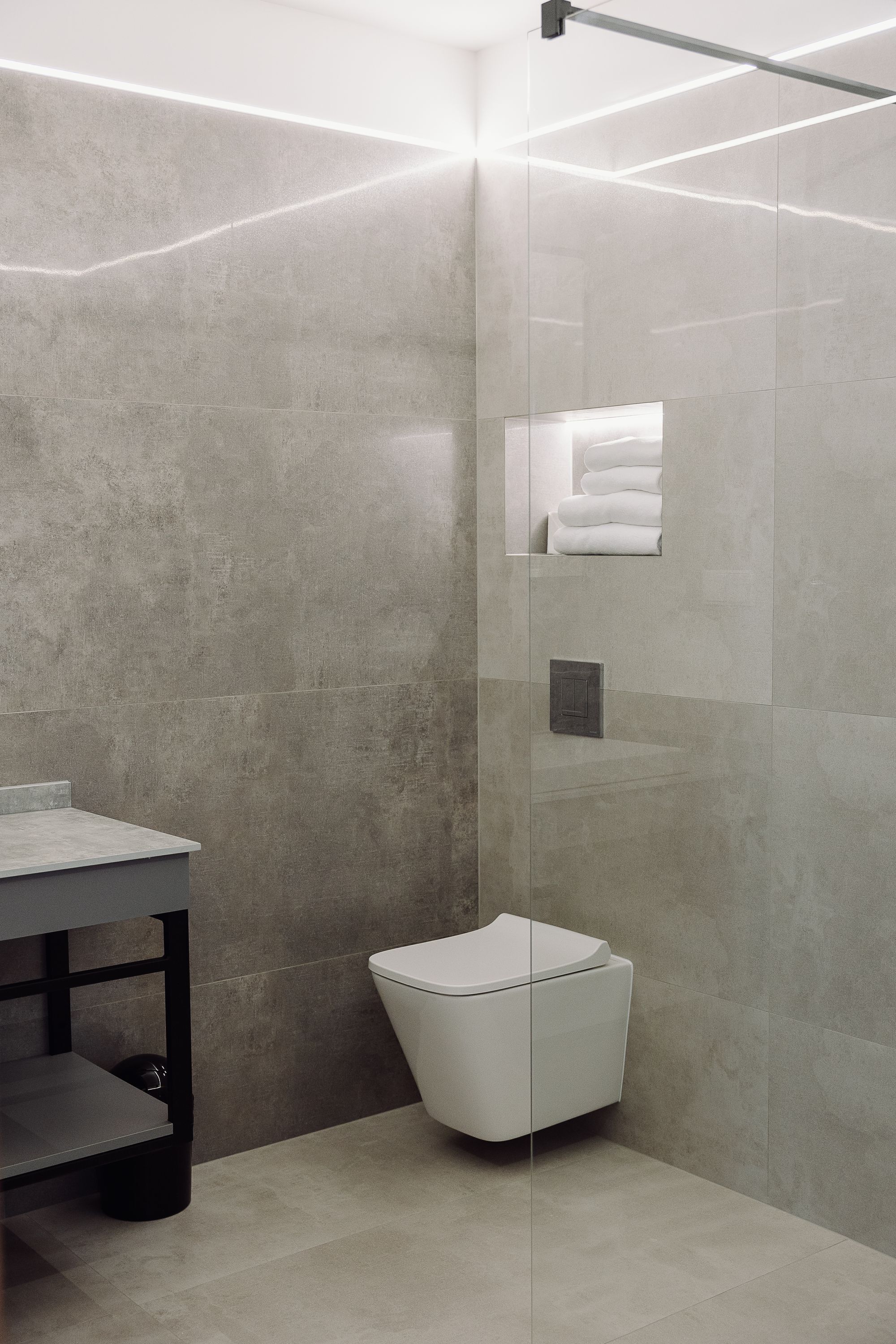 Un baño moderno con cabina de ducha de vidrio, inodoro blanco y lavabo con encimera oscura.