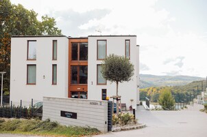 Un edificio moderno con techo plano, ventanas amplias y un pequeño árbol en la parte frontal.