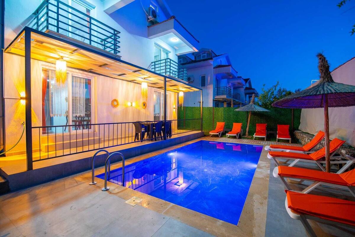 A modern hotel with a swimming pool, outdoor seating, and a covered area.
