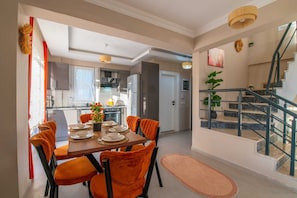 A modern kitchen with a dining area, a staircase, and a view of the living room. - SUREYYA HOTEL BY KALIPSO (Fethiye)