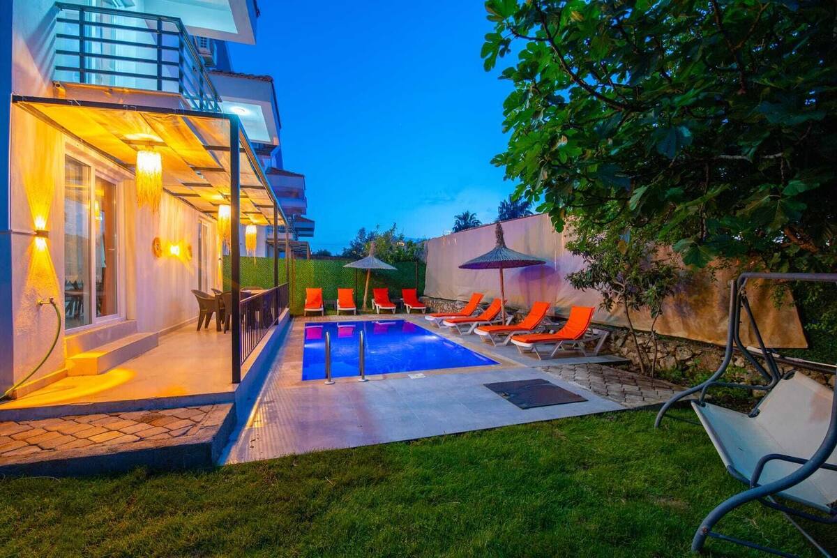 A swimming pool with lounge chairs, a covered seating area, and a staircase leading to an upper level.