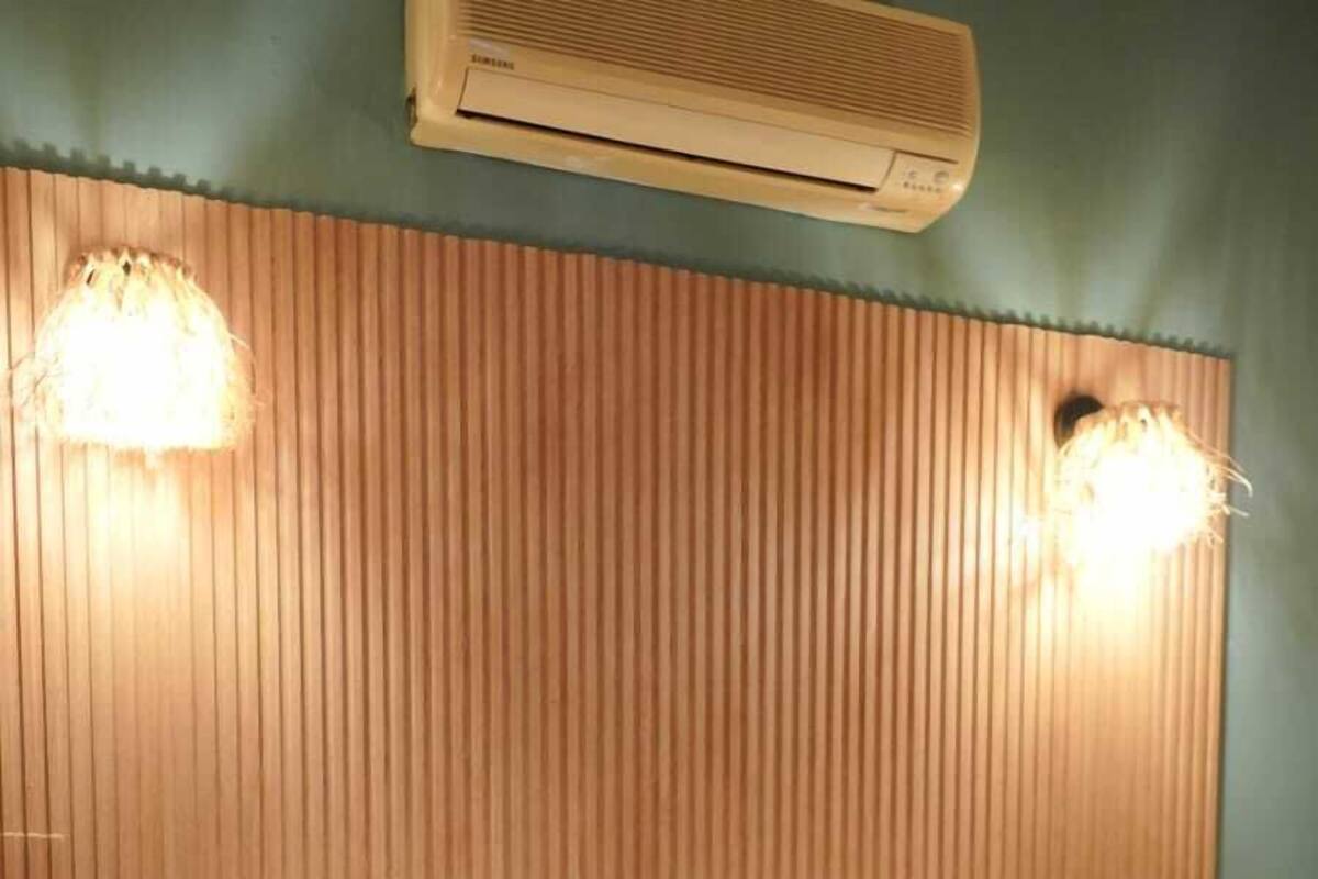 A bedroom with a wooden headboard, a bed with white and brown bedding, and two wall-mounted lights.