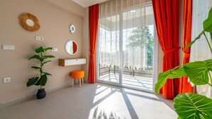 A room with a large window, a potted plant, a small stool, a mirror, and a wall-mounted light fixture. - SUREYYA HOTEL BY KALIPSO (Fethiye)