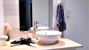 A bathroom with a white sink, a mirror, and a towel hanging on the wall.