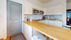 A compact kitchen with white cabinets, a wooden countertop, a microwave, and a sink. - A peaceful country retreat minutes from Watkins Glen—perfect for couples, friends, or family escapes. (Montour Falls)