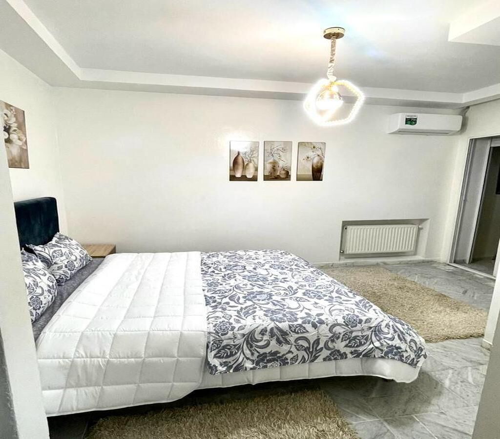 Quarto com cama, luminária no teto, radiador e obras de arte nas paredes.