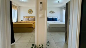 Habitación de hotel con dos camas, un espejo con diseño de sol, un termostato y una planta en maceta.
