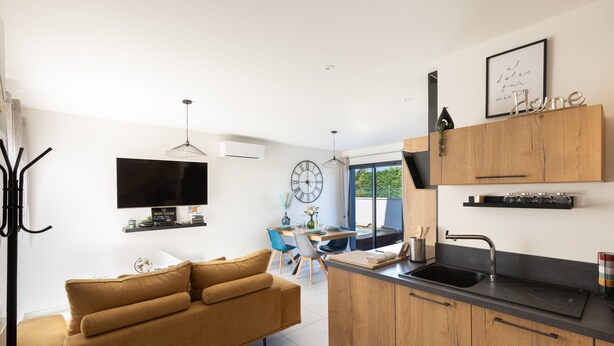 Una cocina moderna con encimera de madera, un lavamanos integrado y un comedor con mesa y sillas.