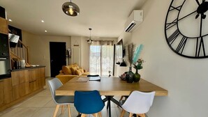 Una cocina moderna con encimera de madera, una mesa de comedor con cuatro sillas y un reloj de pared grande.