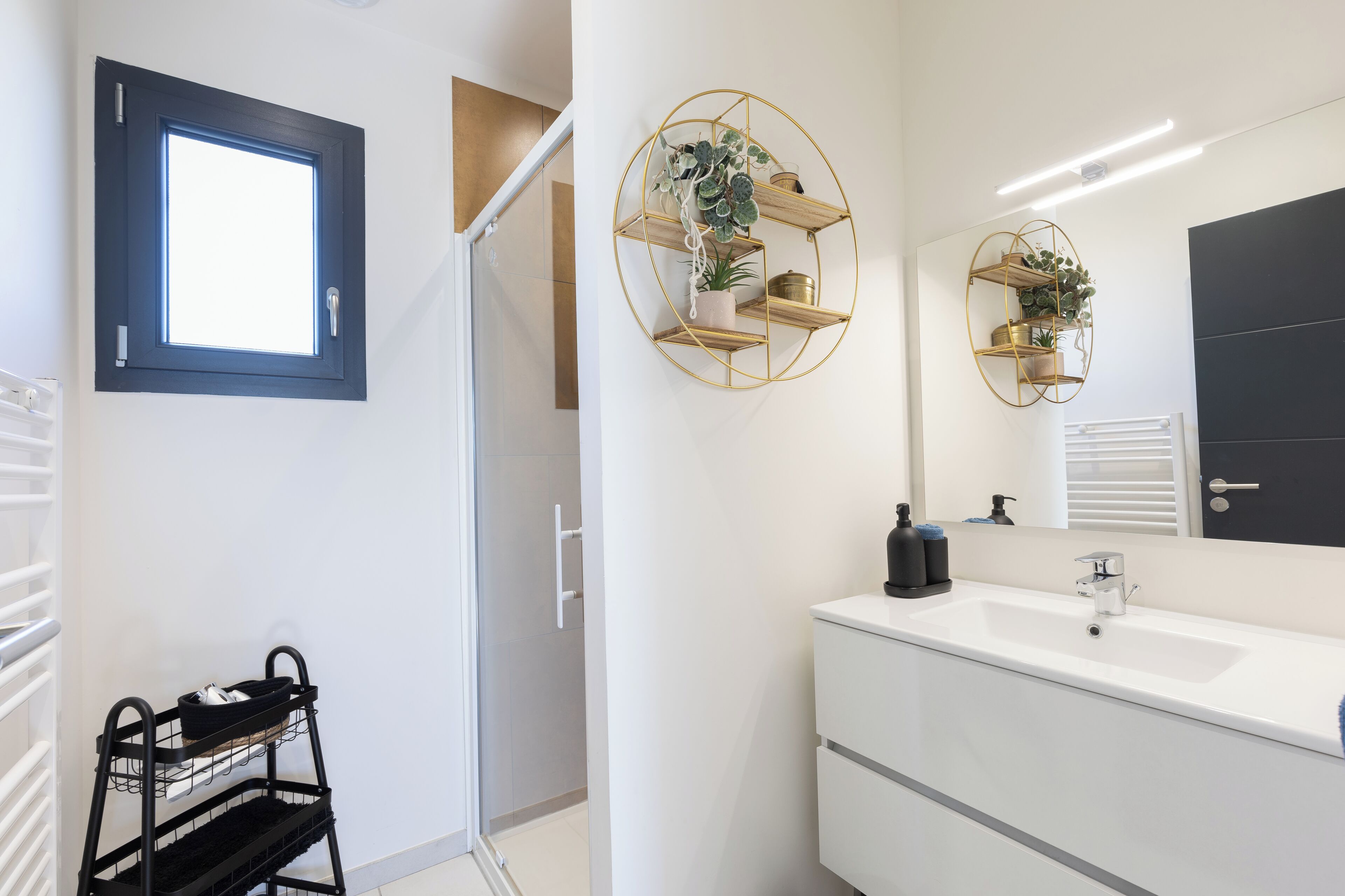 A modern bathroom with a white vanity, a large mirror, and a black door.