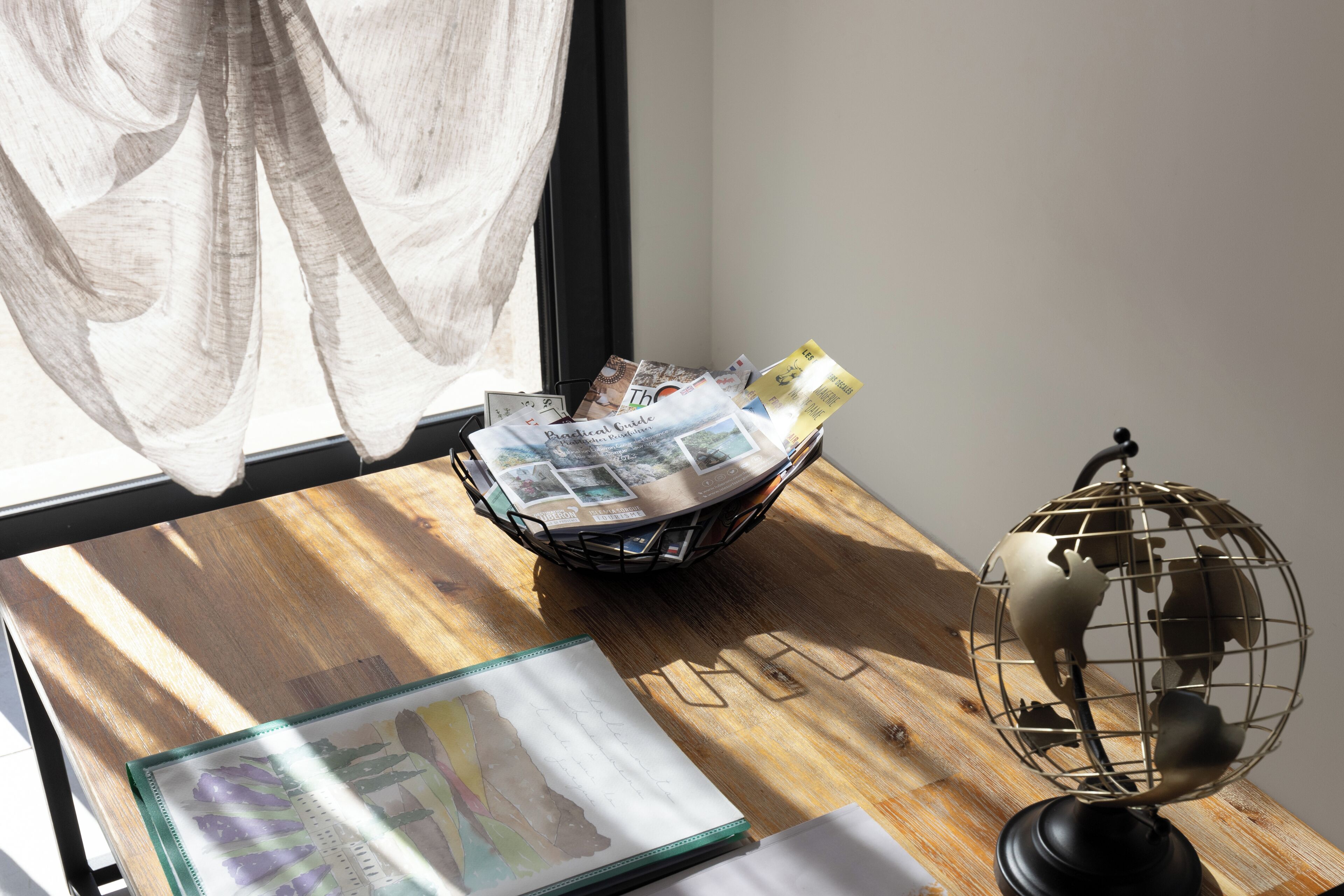 A wooden table with a globe, a basket of magazines, and a framed picture.