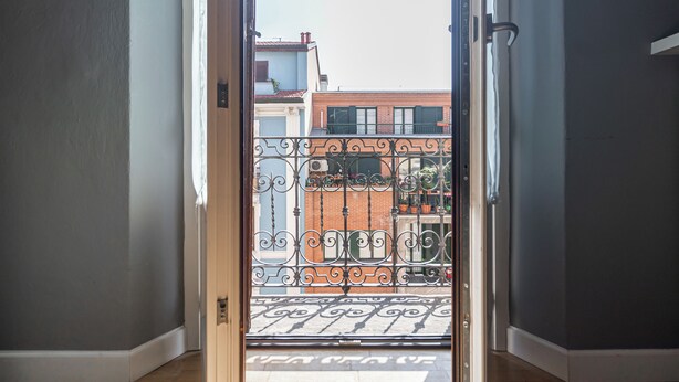 A view through a door with a metal gate leading to a balcony with a tiled floor. - Italianway Easy - Rosmini 13 B (Milan)
