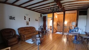 Un ampio soggiorno con pavimento in legno, un divano in pelle, un tavolo da pranzo in legno e un lampadario.