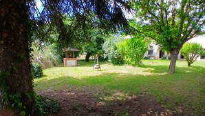 Un giardino con un gazebo, una struttura in mattoni e un albero con un'amaca.