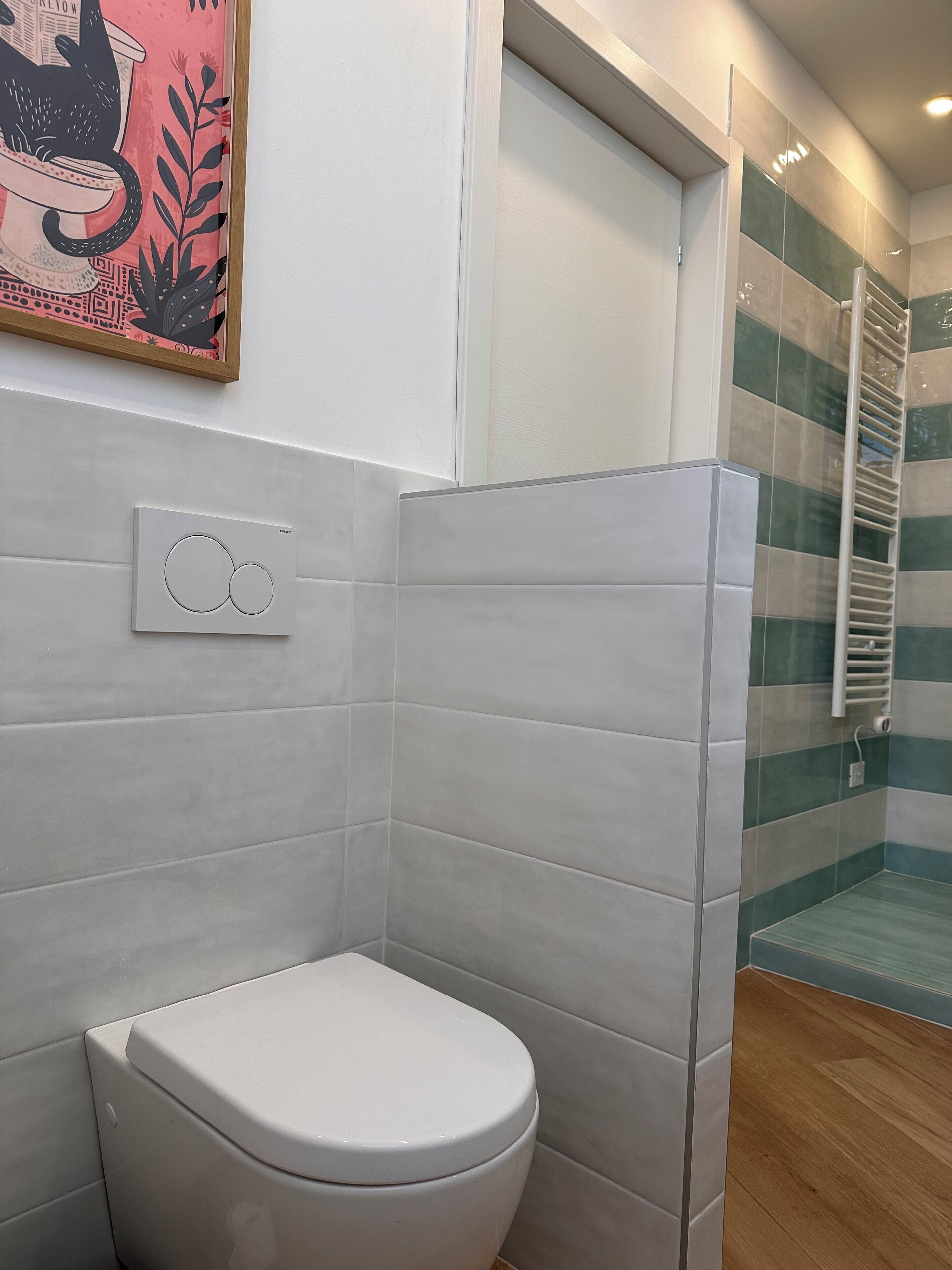 Un baño con inodoro blanco, termostato en la pared y cabina de ducha con puerta de vidrio.
