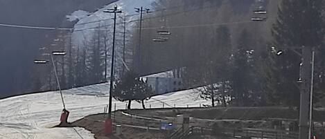 A ski lift with cables and chairs, a snowy mountain in the background, and a clear sky.