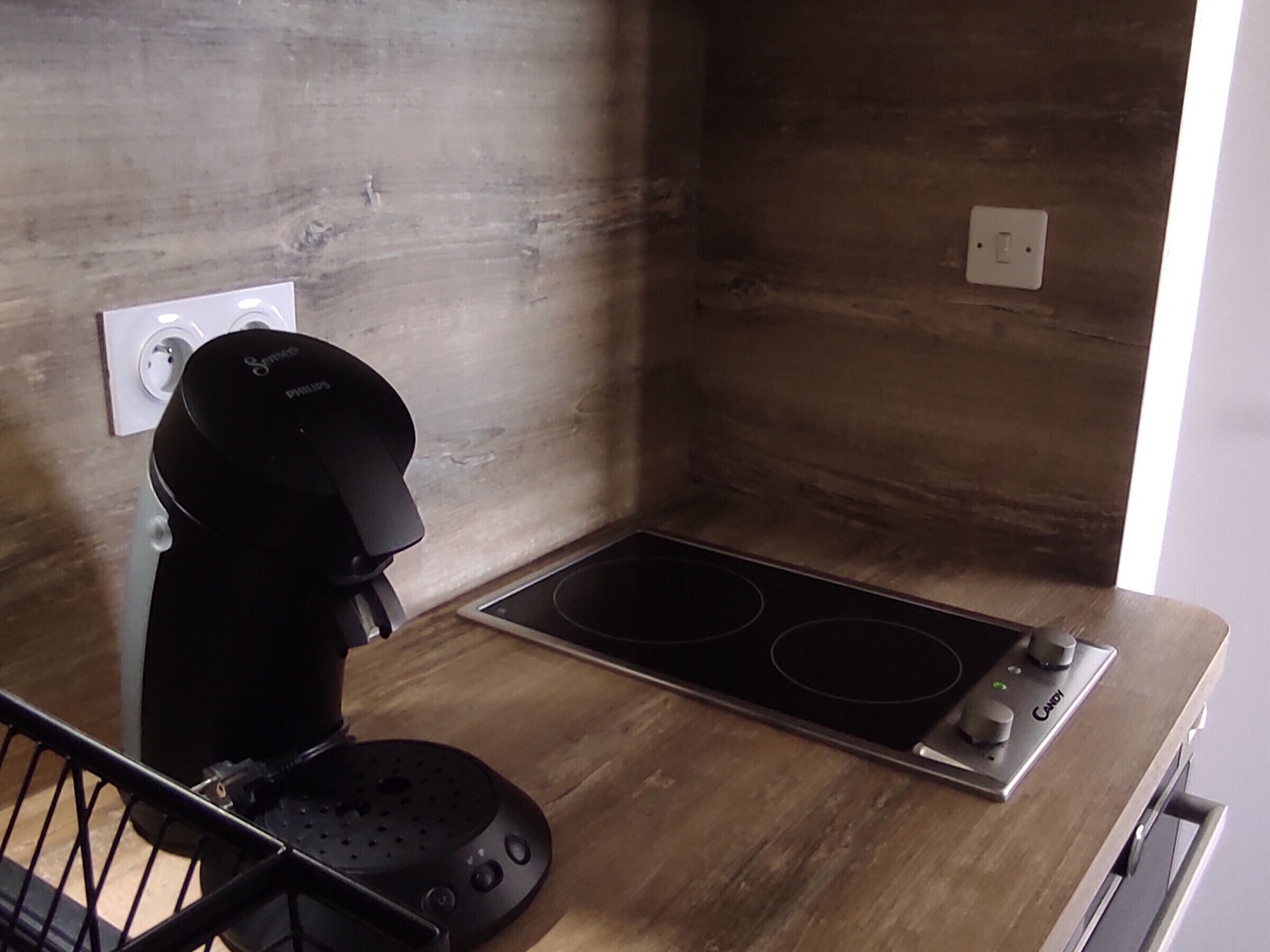 A compact kitchen with a coffee maker, a stovetop, and a power outlet.