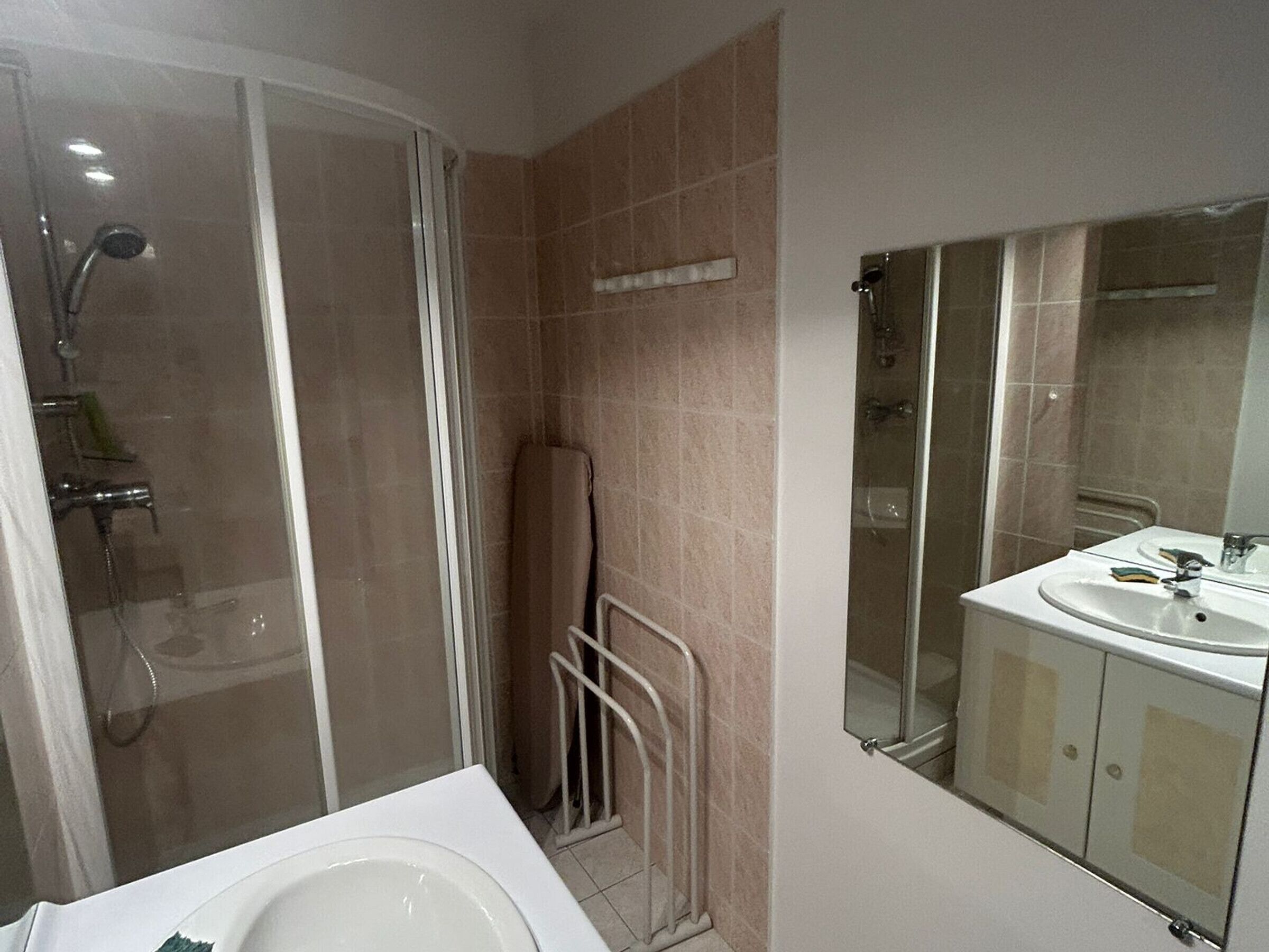 Un baño con ducha, bañera, lavamanos y espejo.