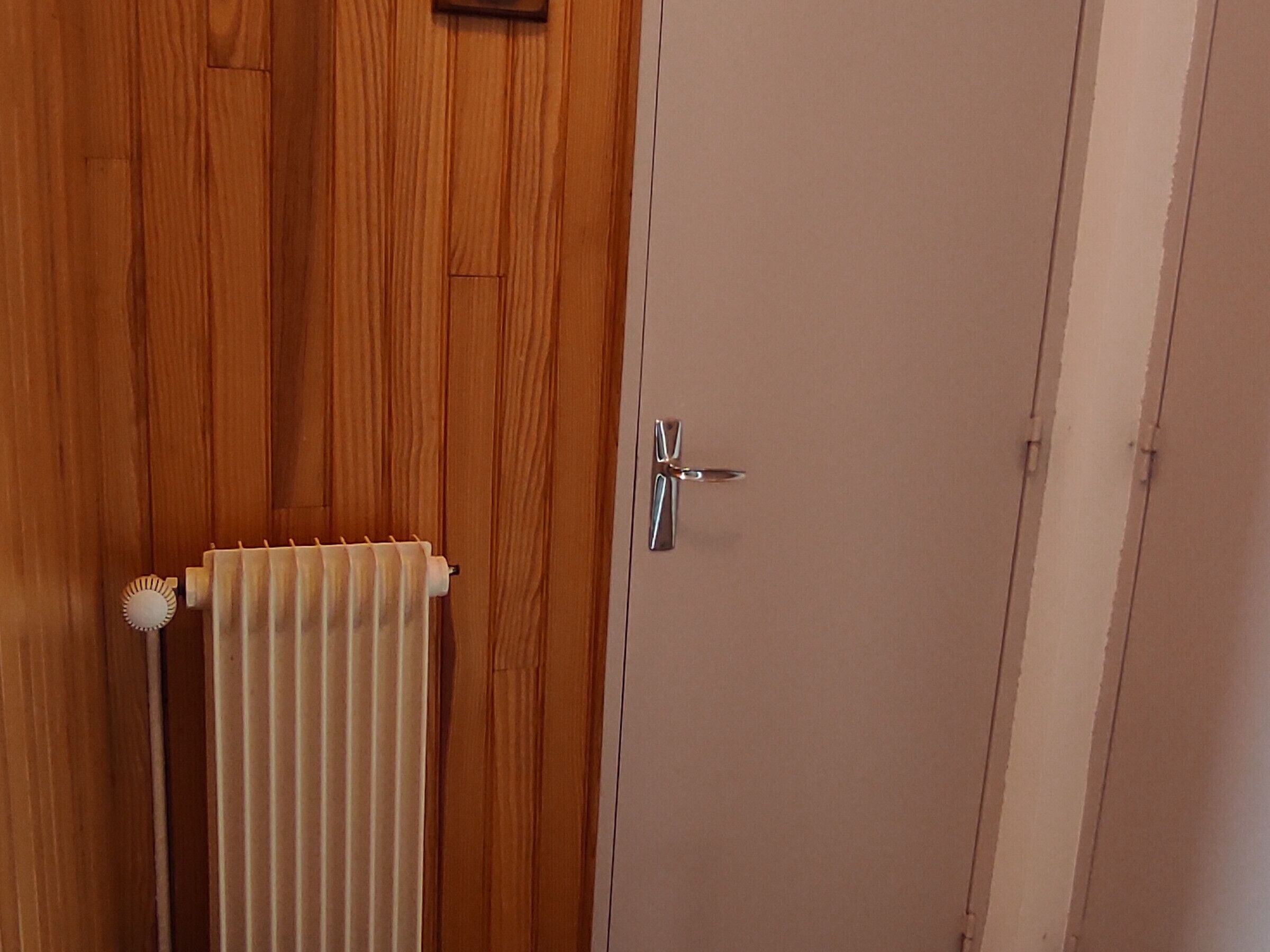 Una puerta de madera con un radiador y un picaporte metálico.