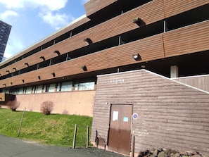 A multi-story building with a wooden facade, a sign reading 'La Fonti,' and a gated entrance.