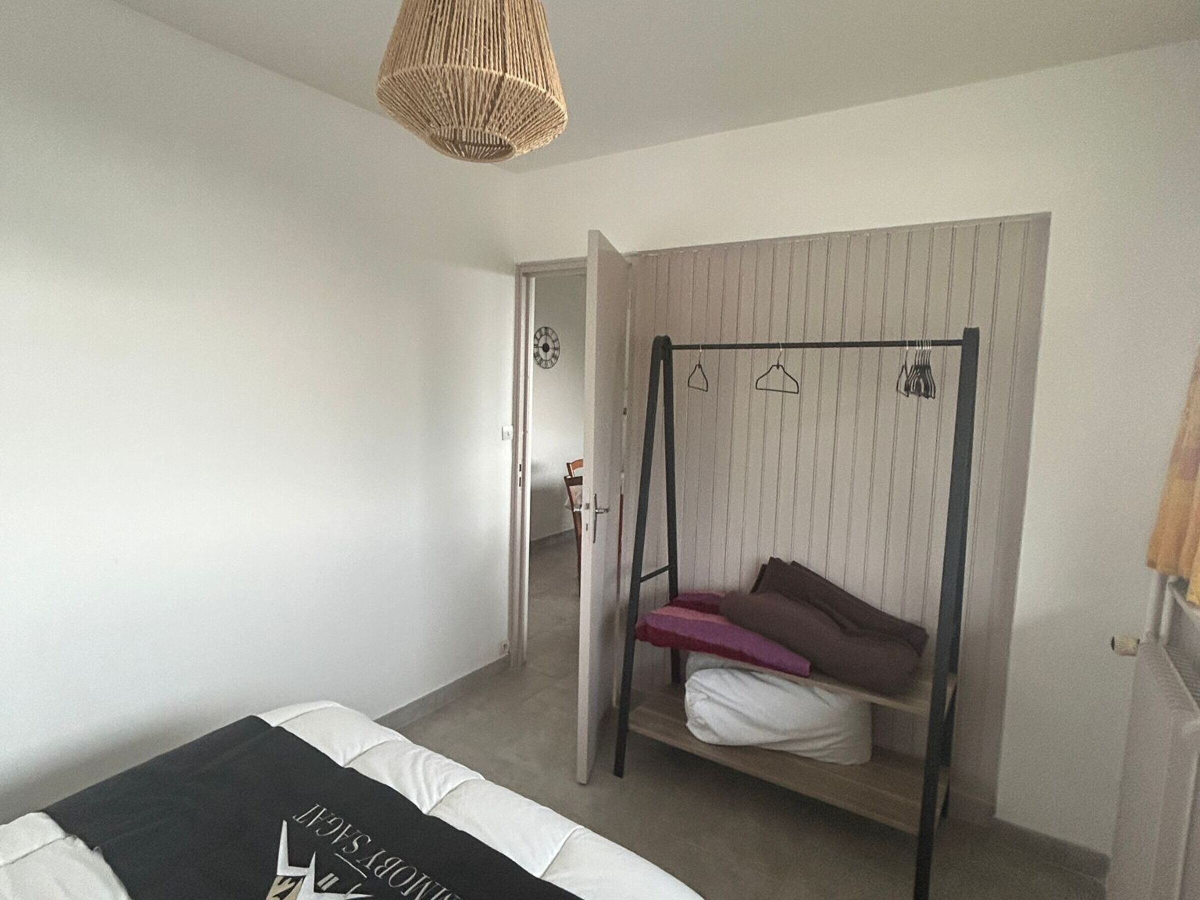 Ein Schlafzimmer mit Etagenbett, Hängesessel, Kleiderschrank und einer Tür zu einem anderen Raum.