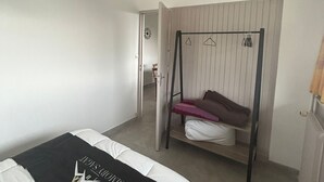 Ein Schlafzimmer mit Etagenbett, Hängesessel, Kleiderschrank und einer Tür zu einem anderen Raum.