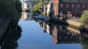 Un fiume tranquillo con barche, una gru e edifici lungo le rive.