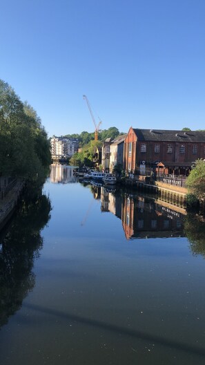 Une rivière paisible, avec des bateaux, une grue et des bâtiments le long des rives.