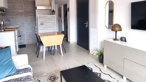 A modern living space with a kitchen, dining area, and a TV mounted on the wall. - T2 Apartment with Terrace in Port-Vendres Center (Port-Vendres)