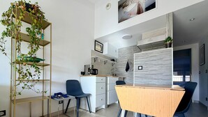 A modern kitchen with a dining area, a coffee machine, and a plant shelf. - T2 Apartment with Terrace in Port-Vendres Center (Port-Vendres)