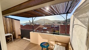 A balcony with a view of a town, a sofa, a small table, and a chair. - T2 Apartment with Terrace in Port-Vendres Center (Port-Vendres)