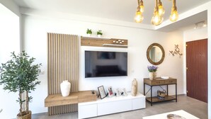 A modern living room with a large flat-screen TV, wooden console, and a dining table.