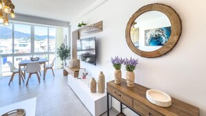 A modern living room with a large window, a dining area, and a wooden console table with decorative items.