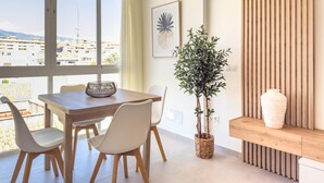 A modern dining area with a wooden table and chairs, a potted plant, and a decorative wall panel.