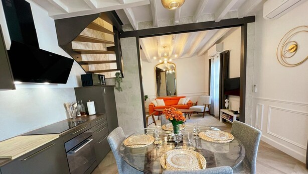 A modern kitchen with a built-in oven and a dining area with a glass table and chairs. - Charming cottage in Langeais with terrace and wifi for 4 people (Langeais)