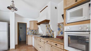 Une cuisine avec des meubles de rangement en bois, une cuisinière à gaz, un four à micro-ondes et un four traditionnel.