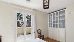 Une chambre à coucher comprenant un lit, une chaise, une porte-fenêtre coulissante et une armoire.